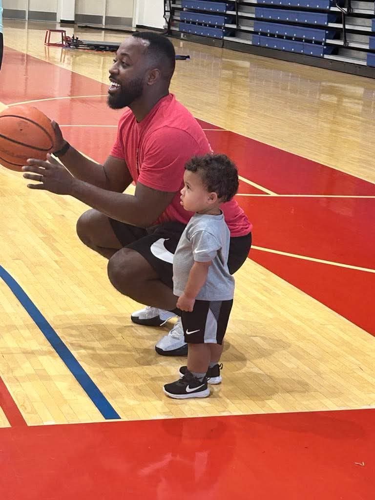 Coach Tirrell smiling courtside with his young child during a TC3 Basketball session in Hillsboro, OH